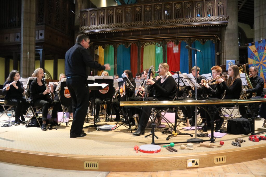 The band performing in a church with a colourful backdrop